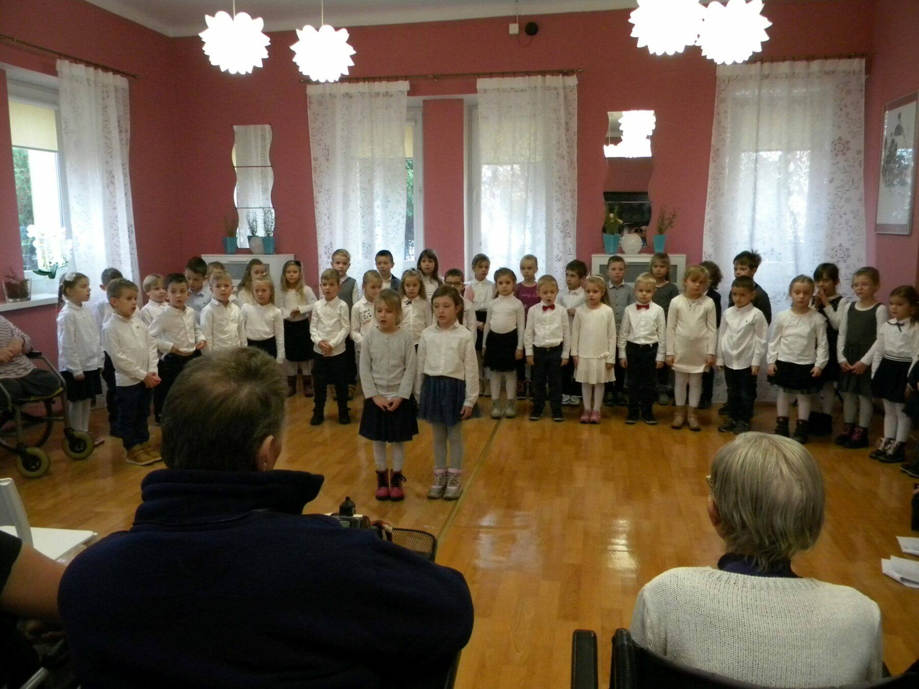 Zebrane dzieci śpiewają ubrane na galowo.
